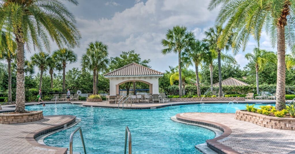 Relaxing tropical poolside scene with palm trees, gazebo, and clear blue water at a luxury resort.