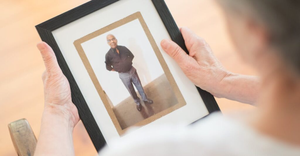 Senior woman holding a framed photo, reflecting on memories and emotional nostalgia.
