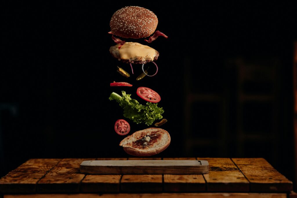 Visually striking deconstructed burger with floating ingredients in a dark background.